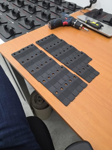 Schwarze, rechteckige Gummimatten mit mehreren Löchern auf einem Tisch.