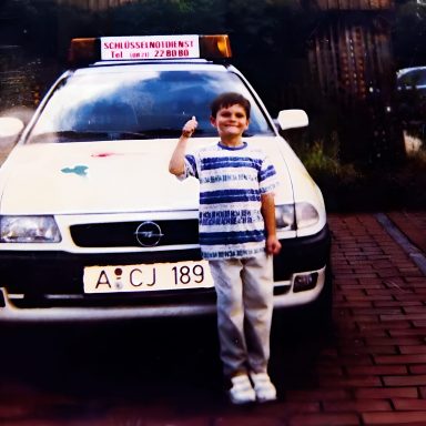 Kleiner Junge, vor einem weißen Schlüsseldienst Auto in Augsburg.